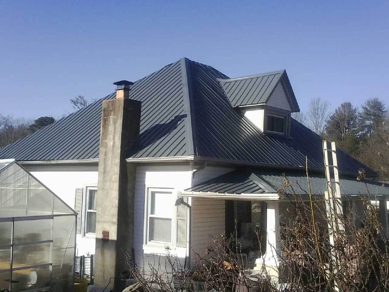 Dark blue standing seam metal roof on a white farmhouse with dormer — Slate & Tile Roof Repair by Roofing Brothers in Greenwood Lake