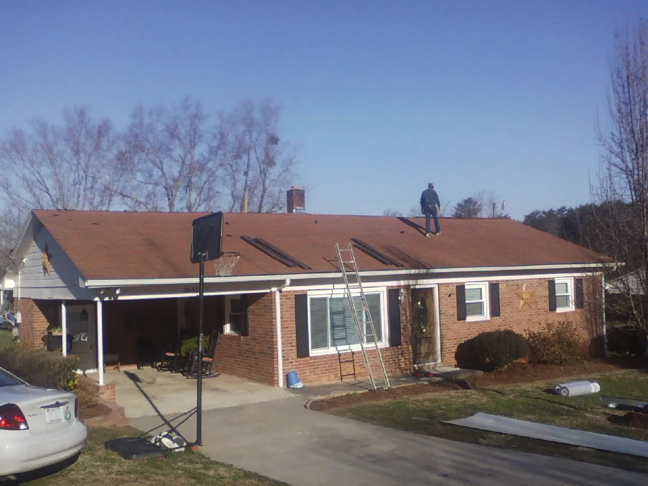 Roofer stripping a shingle roof on a brick ranch before metal panels in Greenwood Lake