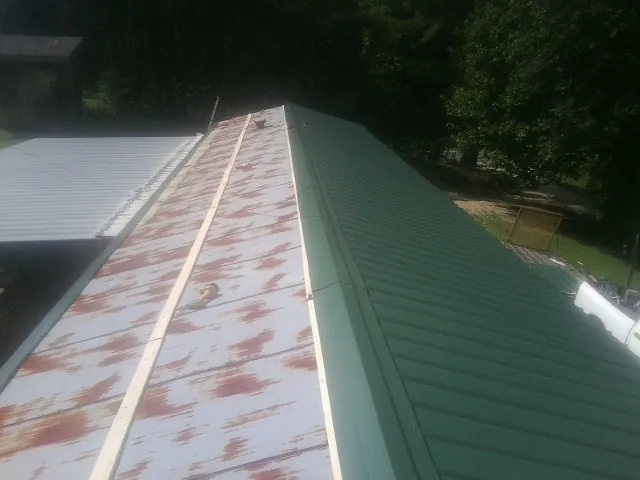 Old rusted panels beside newly installed green metal roofing — Wind Damage Roof Repair by Roofing Brothers in Greenwood Lake