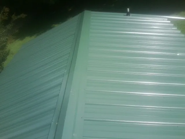 New green metal panels meeting at the ridge of a roof — Flat Roof Repair work by our crew in Greenwood Lake