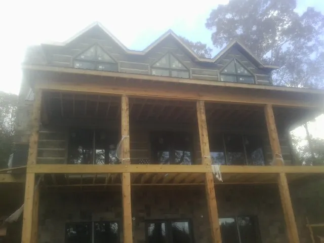 Dormers and porch framing on a large log home under construction — Roof Coating work by our crew in Greenwood Lake