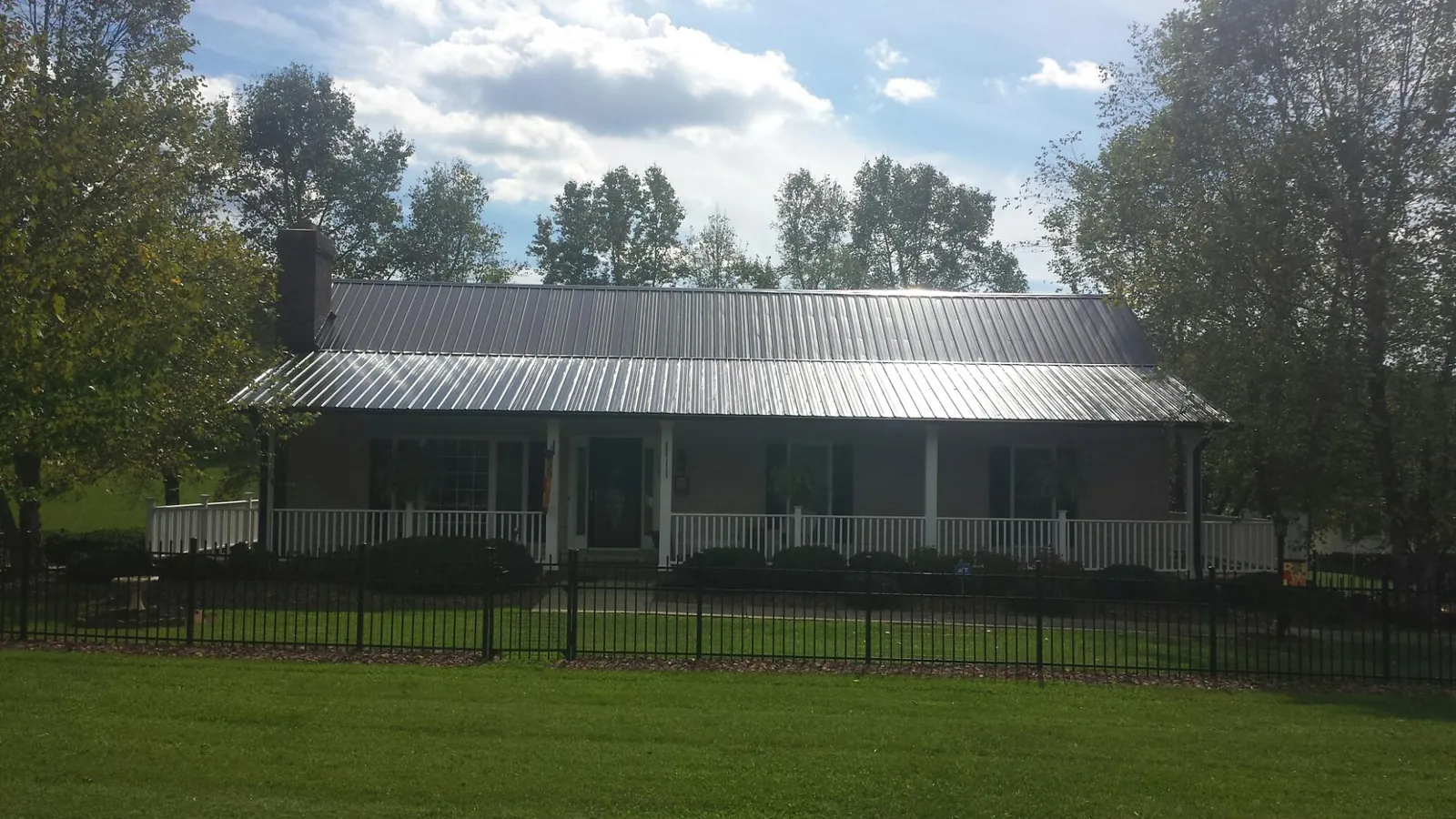 Gray metal roof on a brick ranch with a full width front porch — Gutter Guard Installation work by our crew in Greenwood Lake