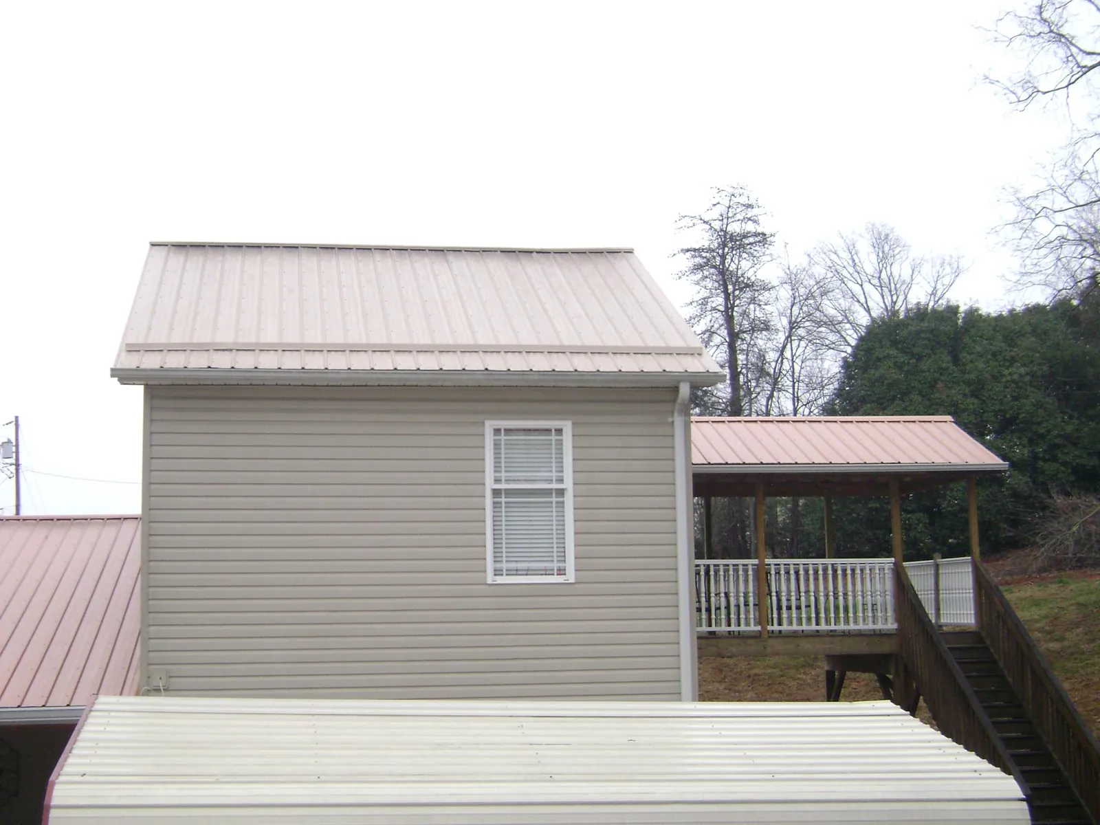 Tan metal roofs on a two story addition and attached porch, from a Roof Replacement job in Greenwood Lake