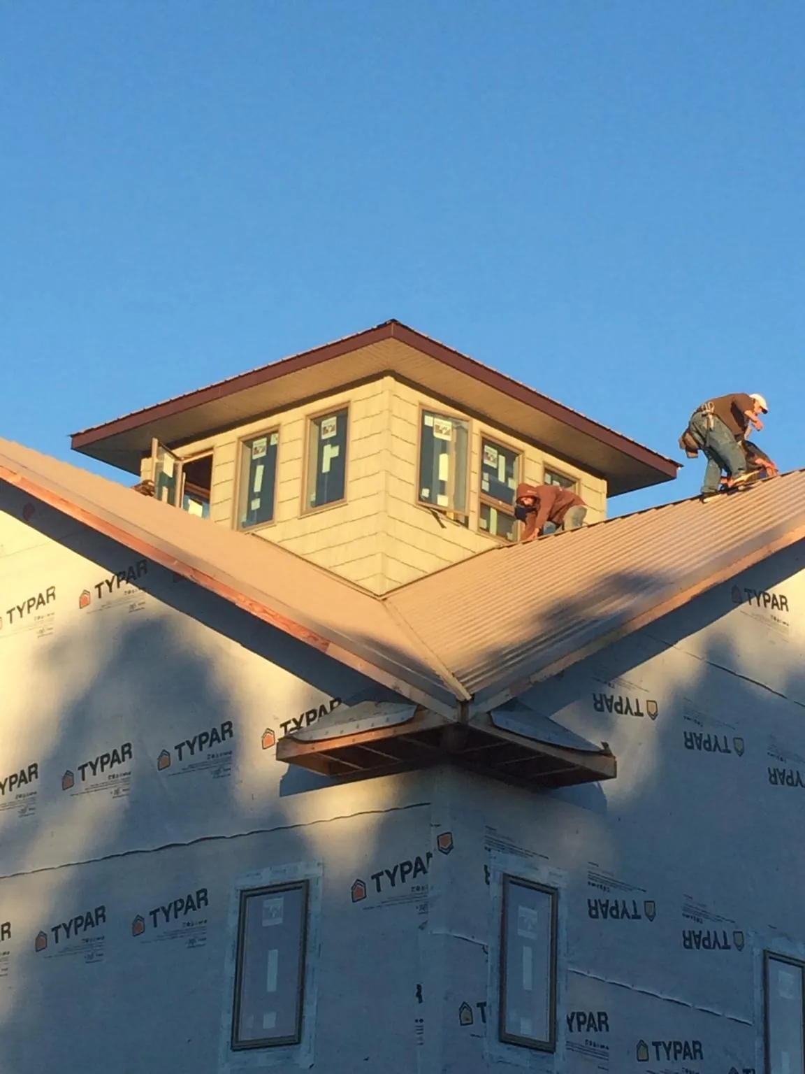 Roofers working around a rooftop cupola on a new metal roof at sunset — Roof Waterproofing in Greenwood Lake by Roofing Brothers